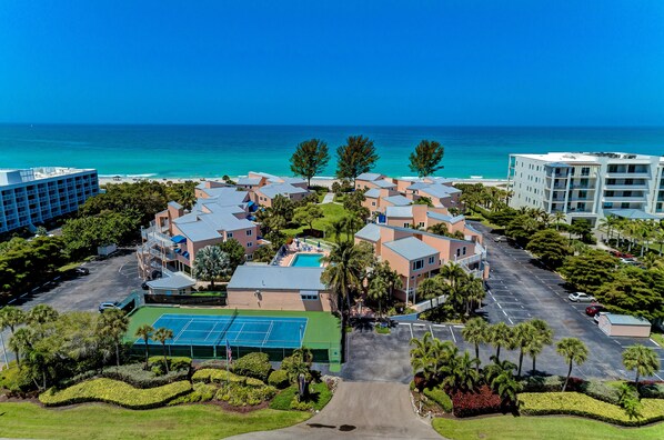 A resort with a central pool, tennis courts, and a view of the ocean. - Unit #111 Sand Cay Beach Resort Pool View (Longboat Key)
