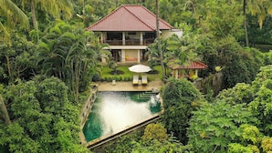 A house with a red-tiled roof, surrounded by lush greenery and a swimming pool. - Bali's Finest, Luxurious Villa Tunjung with Private Pool&Staff in Unspoiled Bali (Seririt)