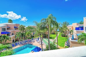 Un resort con piscina, sillas de descanso y palmeras.