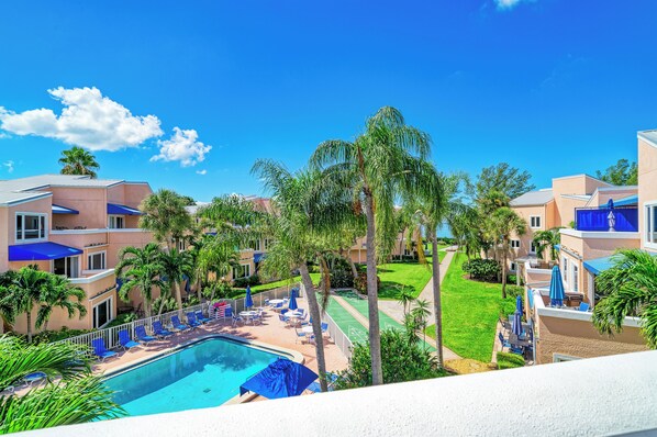A resort with a swimming pool, lounge chairs, and palm trees.
