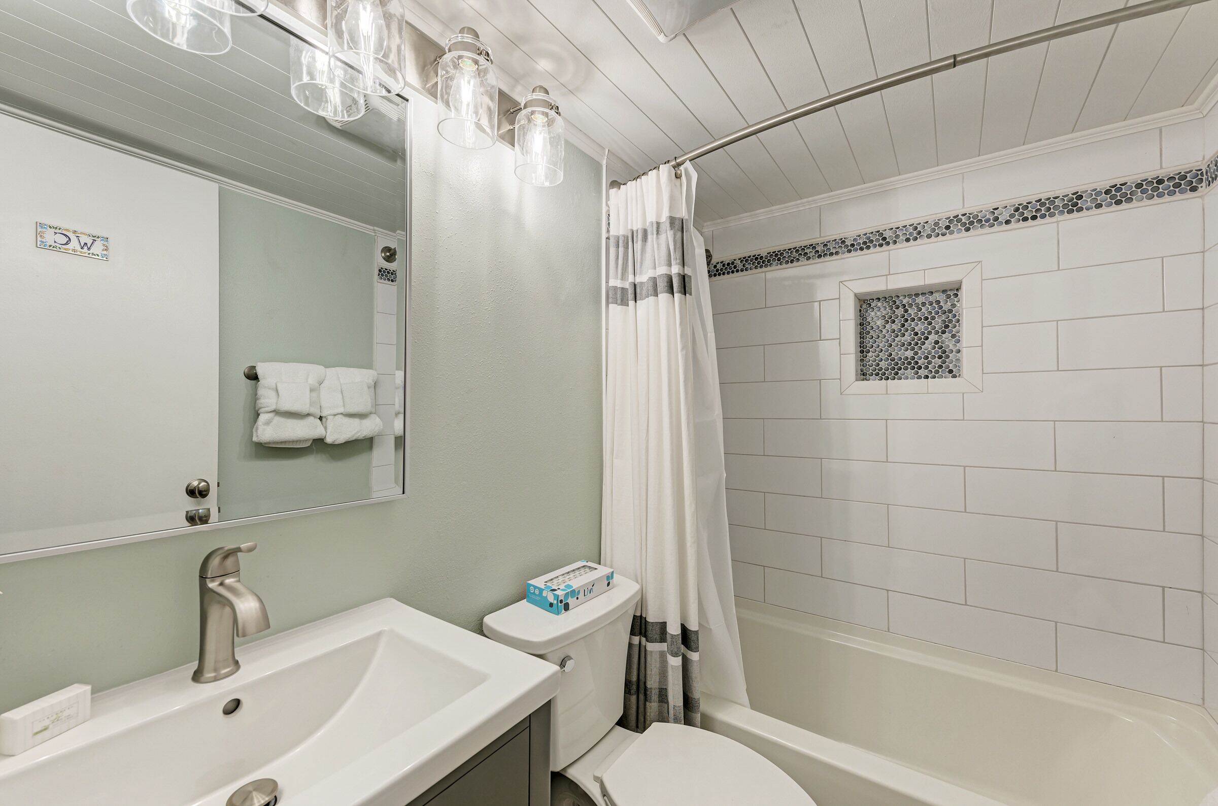 A bathroom with a sink, toilet, and shower area.
