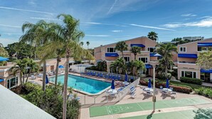 Un hôtel doté d’une piscine, de chaises longues et d’un court de tennis.
