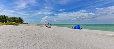 A beach with a clear sky, a few umbrellas, and a tent.