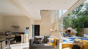 Uma sala de estar moderna com cozinha, área de jantar e vista para uma piscina.
