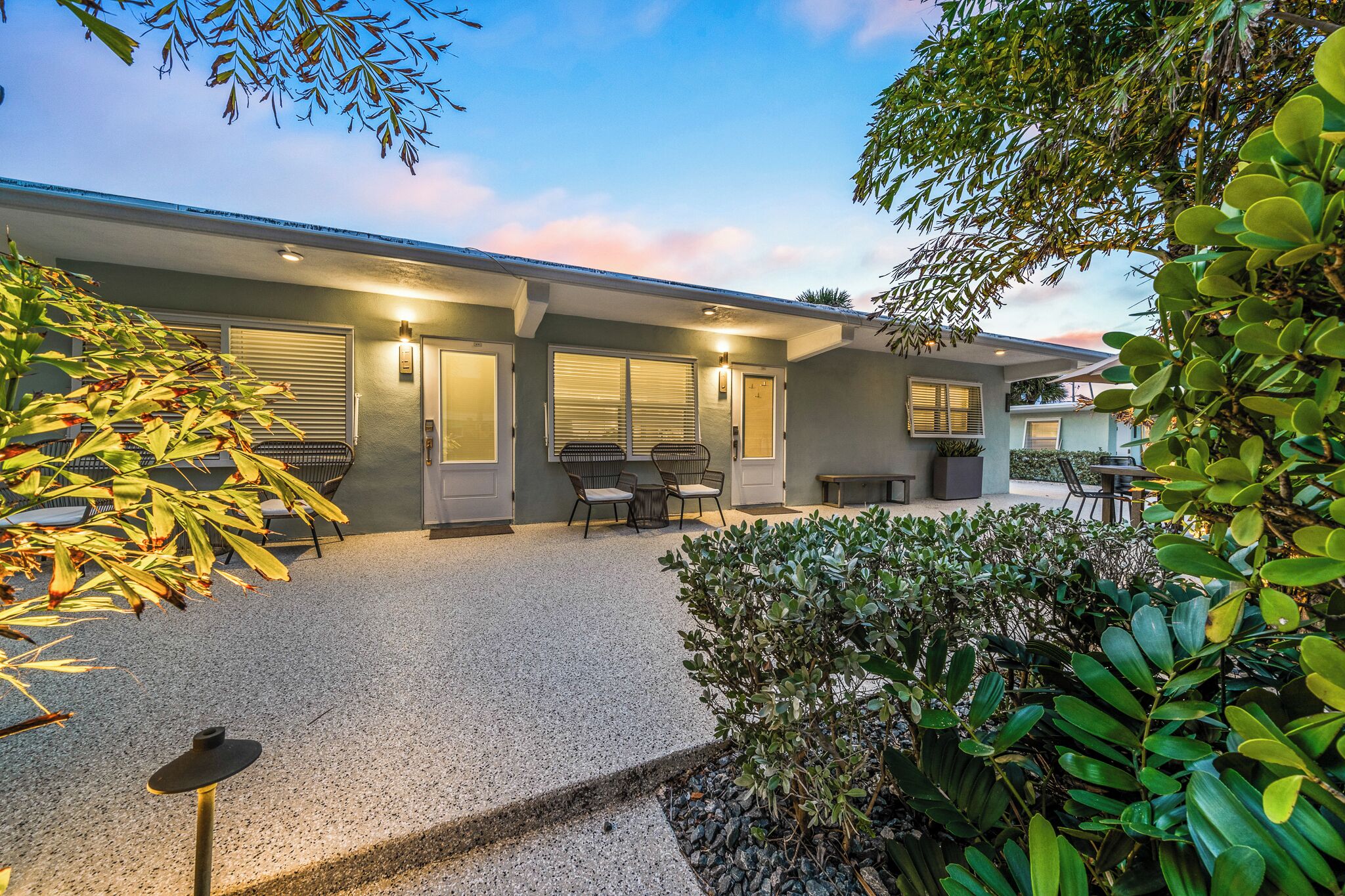 A modern building with a covered patio area, outdoor seating, and a well-maintained garden.