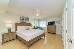 Une chambre à coucher comprenant un lit, une table de chevet, une commode et un ventilateur de plafond.