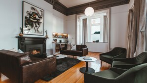A living room with a fireplace, leather sofas, a coffee table, and a bookshelf. - Maylands Lodge (New Town)