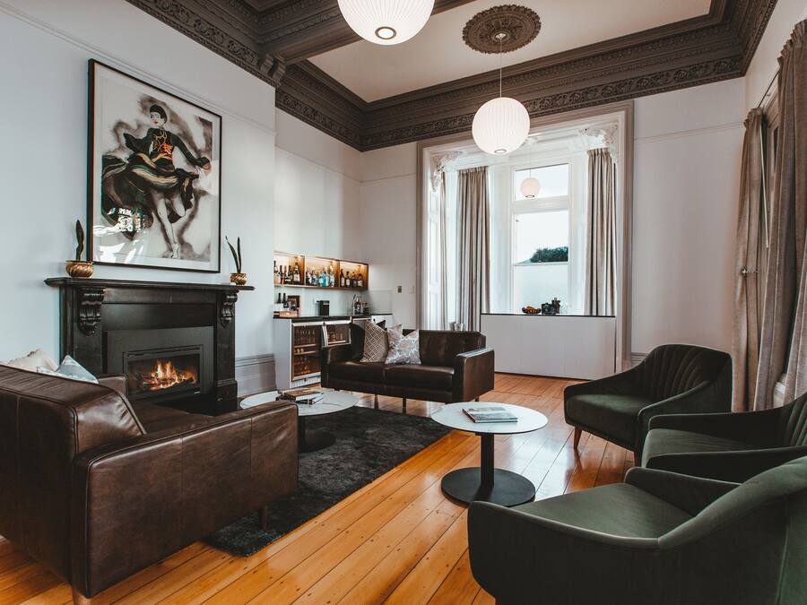A living room with a fireplace, leather sofas, a coffee table, and a bookshelf.
