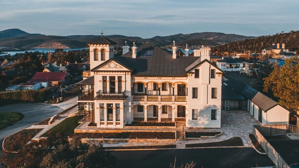 A large, historic building with a prominent tower, multiple balconies, and a spacious front porch. - Maylands Lodge (New Town)