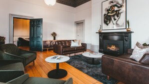A living room with a fireplace, a large framed artwork, and a dark green sofa. - Maylands Lodge (New Town)