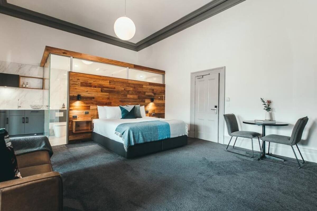 A modern bedroom with a wooden headboard, a bed, a desk, and a chair.