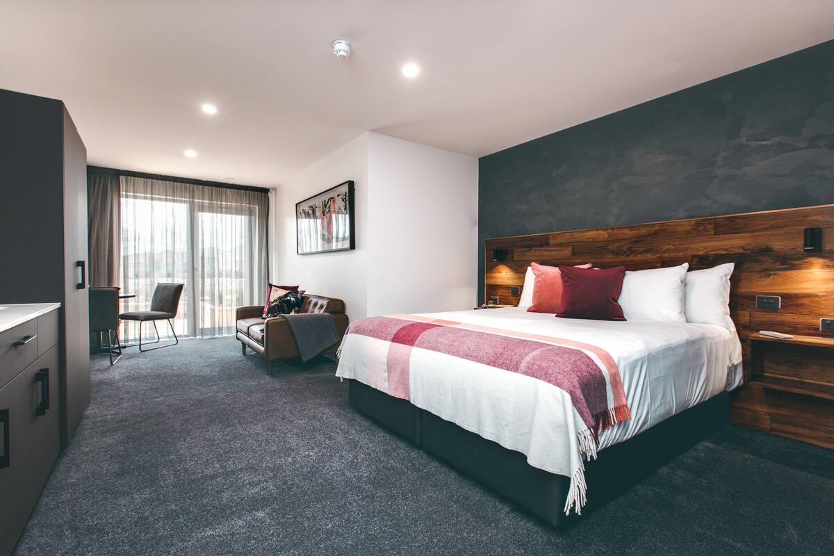 A modern hotel room with a large bed, a desk, and a chair.