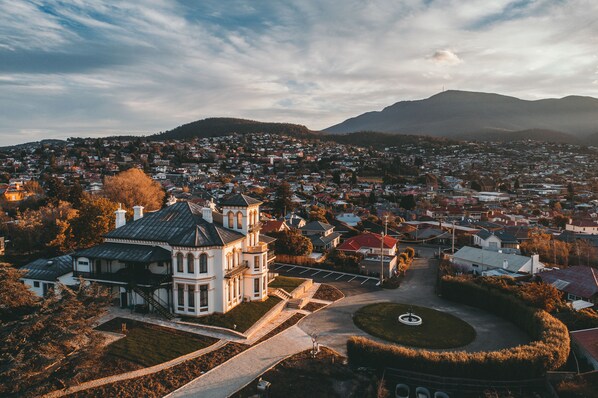 An aerial view of a town with a prominent white building with a tower, surrounded by residential houses and a mountain in the background. - Maylands Lodge (New Town)