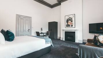 Una habitación de hotel con cama, chimenea, televisión y zona de comedor.