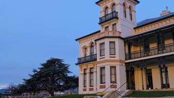 A historic building with a prominent tower, large windows, and a balcony with ornate railings.