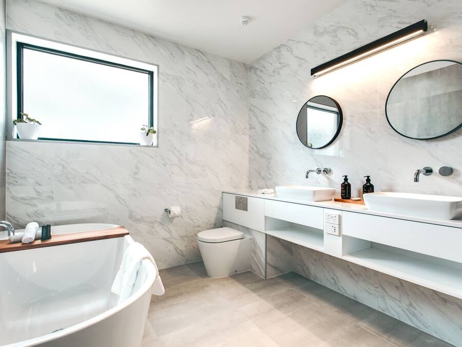 A modern bathroom with a freestanding bathtub, a large mirror, and a white vanity with a sink and countertop.