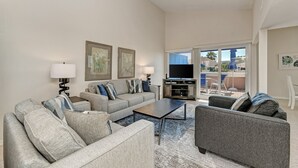 A living room with a sofa, armchairs, a coffee table, and a TV.