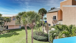 A building with a flat roof, surrounded by a well-maintained lawn and palm trees.