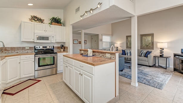 A modern kitchen with white cabinetry, a built-in microwave, and a large island.