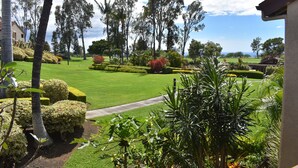 Un jardin bien entretenu, avec des haies taillées avec soin, une variété d’arbres et une vue dégagée sur un terrain de golf au loin.