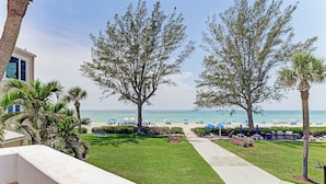 A beachfront view with a pathway leading to beach umbrellas and lounge chairs.