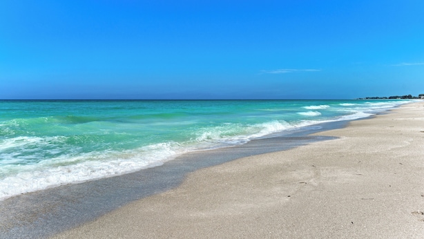 A beach with clear turquoise water and a sandy shore.