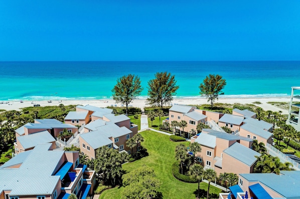 A resort with multiple buildings, a beach, and a clear blue sky.
