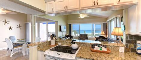 A kitchen with granite countertops, white cabinetry, a built-in oven, and a large window offering a view.
