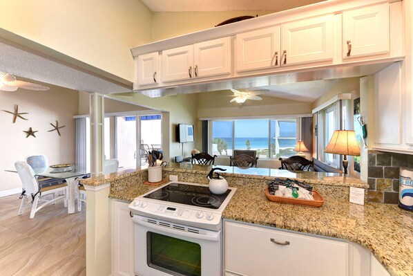 A kitchen with granite countertops, white cabinetry, a built-in oven, and a large window offering a view. - Unit #301 Sand Cay Beach Resort Gulf View 7 Night Minimum (Longboat Key)
