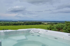 A hot tub with a view of a green landscape and distant mountains. - 2-bed Woodland Lodge with private hot tub and expansive views. (Forres)