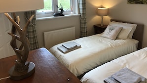 Una camera da letto con due letti, una finestra con tende, una lampada, un termosifone e un quadro appeso al muro.