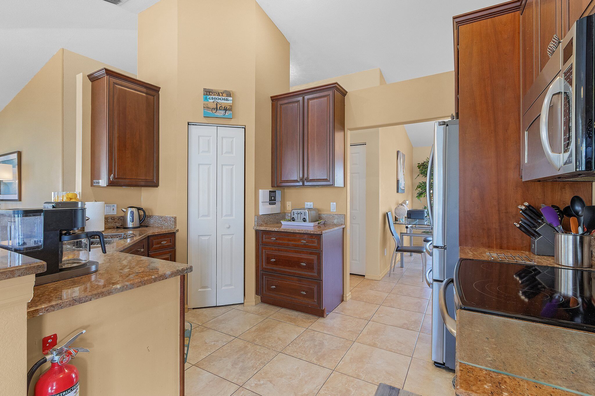 A kitchen with wooden cabinets, a microwave, a refrigerator, and a coffee maker.