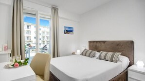 Un cuarto de hotel con una cama grande, una mesita de noche, una silla y vistas de la ciudad desde la ventana.