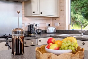 A kitchen with a coffee maker, toaster, and a bowl of fruit on the counter.