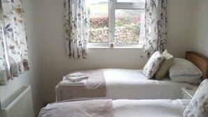 Une chambre avec deux lits simples, un radiateur et une fenêtre avec des rideaux.
