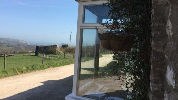 Un bâtiment doté d’une grande fenêtre donnant sur un paysage rural.