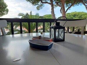 A table with a blue bowl, a red bowl, and a black lantern on a balcony with a railing. - Magnificent apartment in L'Escala  in a beautiful residence  swimming pool (L'Escala)