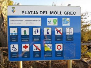 A sign with various symbols and text for Playa del Moll Grec, including beach care, environmental education, and access information. - Magnificent apartment in L'Escala  in a beautiful residence  swimming pool (L'Escala)