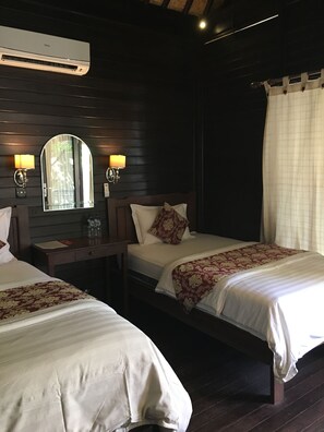 A hotel room with two beds, a wooden headboard, a nightstand, a mirror, wall sconces, and an air conditioning unit. - Tarci Bungalows Lembongan (Lembongan Island)
