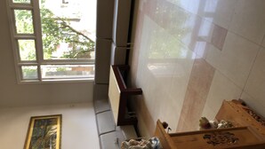 A room with a large window, a framed artwork on the wall, and a wooden chest with decorative items.