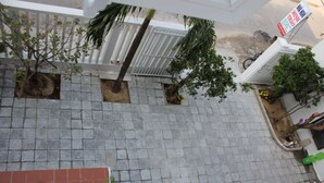 A tiled courtyard with small trees and a white fence.