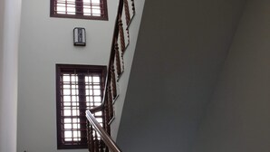 A staircase with wooden balusters and a handrail, leading to a landing with two windows.
