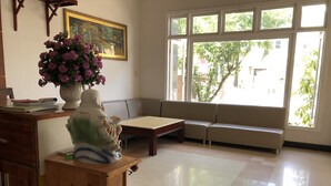 A living room with a sofa, a wooden cabinet, a table, and a vase of flowers.