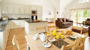 Una cocina amplia con electrodomésticos modernos, un comedor con mesa para desayunos, y una sala de estar acogedora con sofá y mesa de centro.