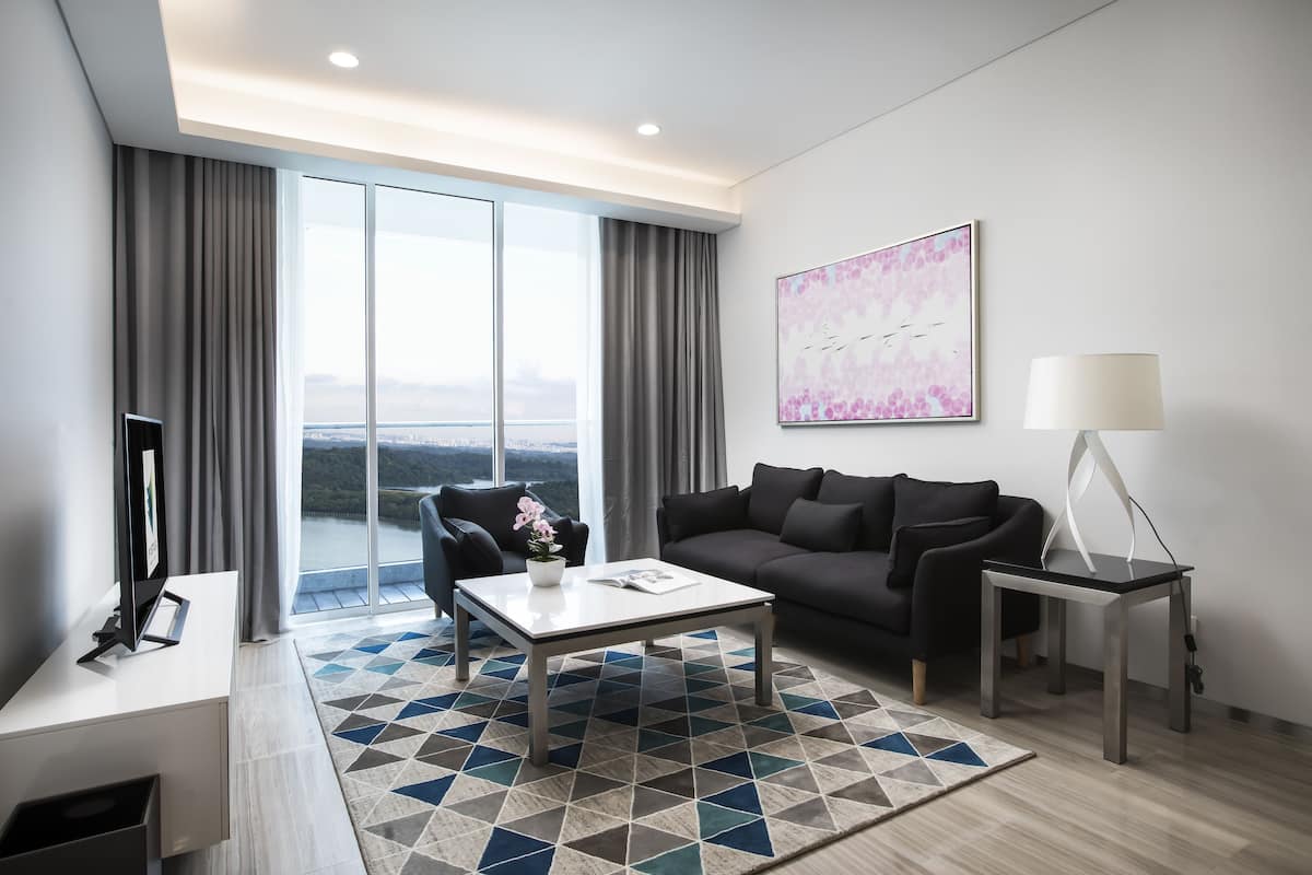 A modern living room with a large window, a sofa, a coffee table, and a TV.