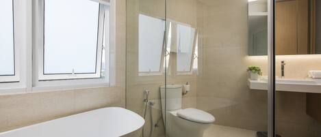 A modern bathroom with a freestanding bathtub, a toilet, and a glass-enclosed shower area.