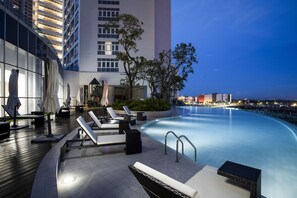A rooftop pool area with lounge chairs and umbrellas, surrounded by modern buildings and a clear sky. - Pinetree Marina Resort (Iskandar Puteri)