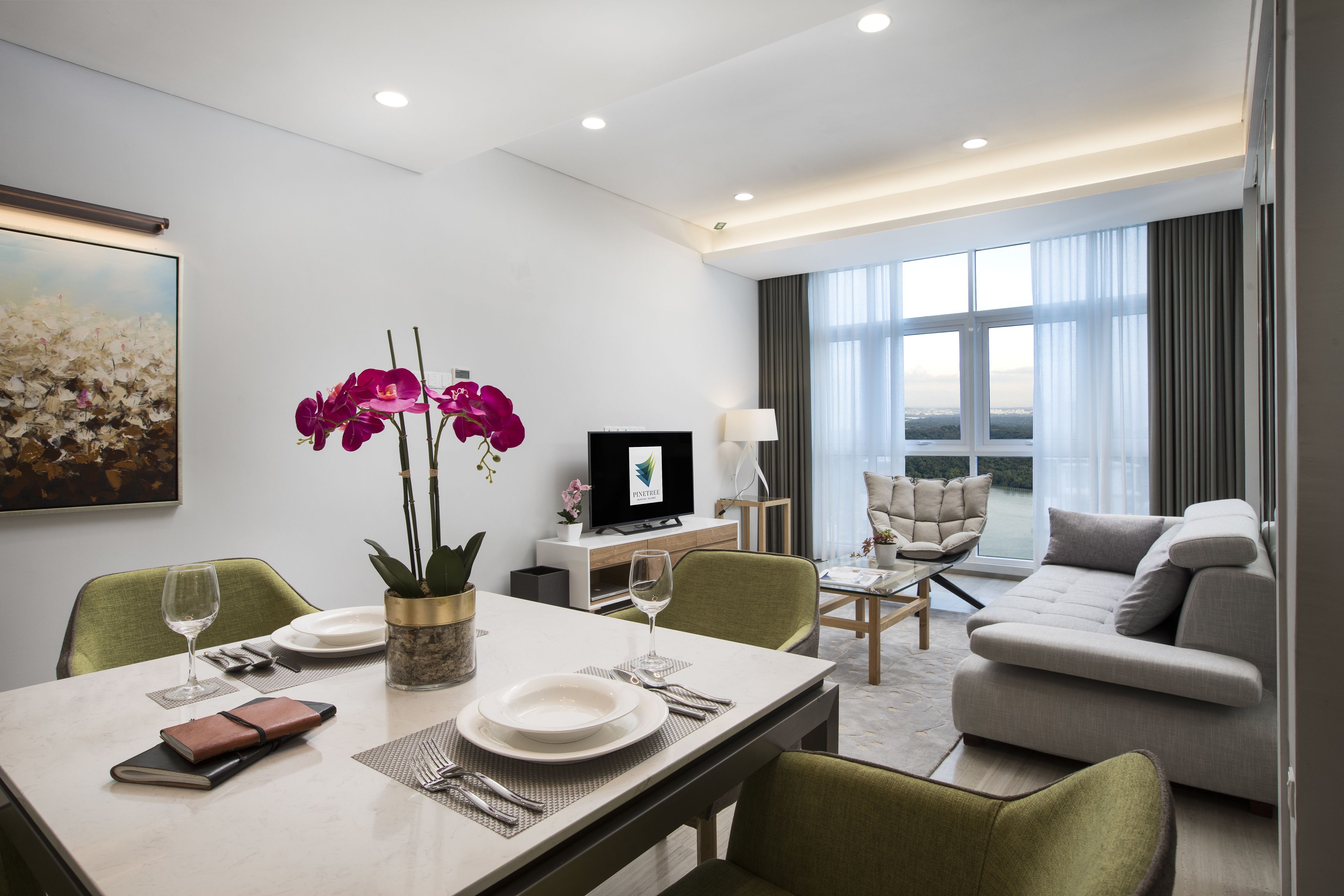 A modern hotel room with a dining area, a sofa, and a TV.