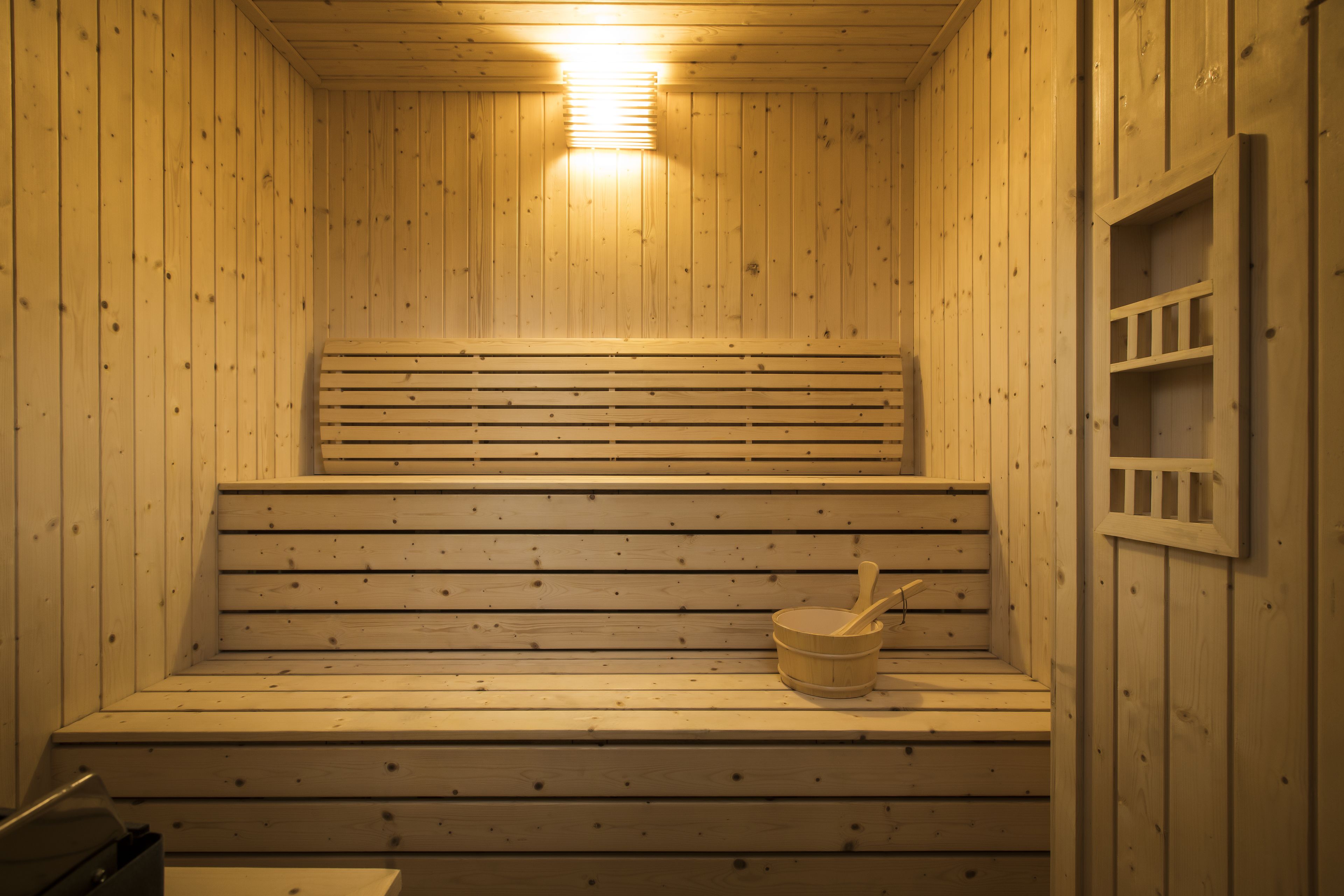 A wooden sauna with benches and a bucket.