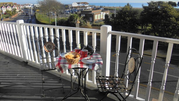 A balcony with a table set for two, a chair, and a decorative item. - Seabreeze Apartment – Stunning Sea Views & Perfect Location (Eastbourne)